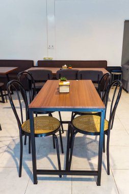 Temiz ve rahat bir kafeterya. Ahşap masalar ve siyah sandalyeler boş bir yemek alanında düzgünce yerleştirilmiş.