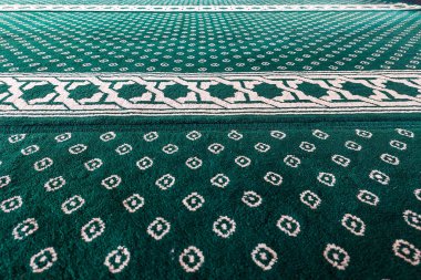 Beyaz geometrik ve çiçek motifli yeşil desenli halılara yakın çekim.