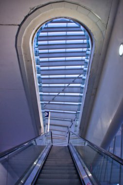 Modern binanın iç mimarisi: bir istasyondaki tırmanan bir yürüyen merdivenden alt-üst perspektif. Çağdaş mimari.