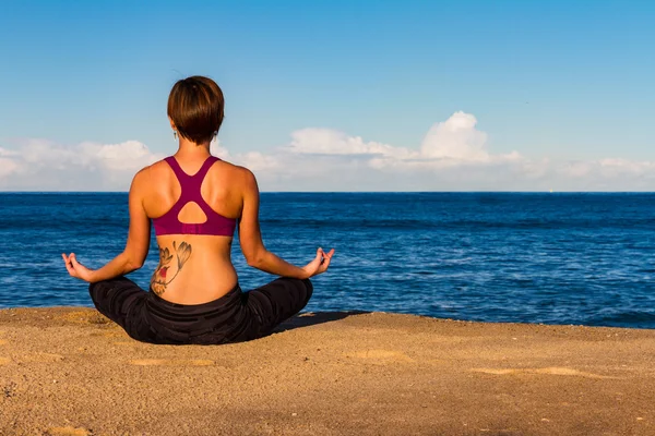 Giovane donna fa Yoga su una spiaggia Immagini Stock Royalty Free