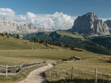 Seceda yürüyüş parkurundan Dolomiti Alpleri 'nin panoramik bir görüntüsü, açık gökyüzünün altında sivri tepeler ve alp vadileri yer alıyor..