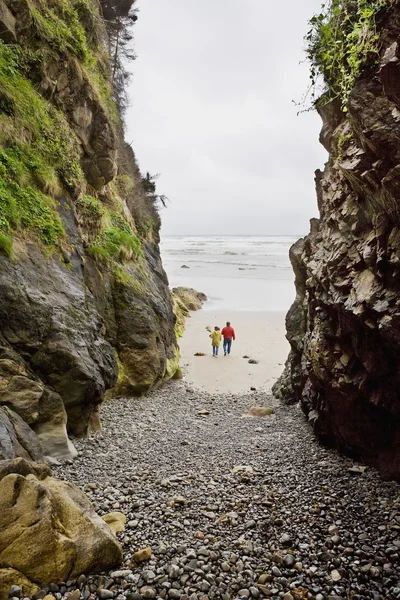 Due persone camminano sulla spiaggia tra grandi rocce — Foto Stock