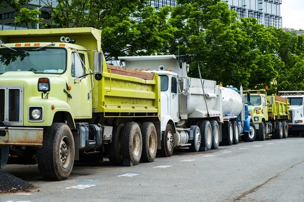 Bir satırda inşaat kamyonları, bazı sarı, bazı beyaz Park