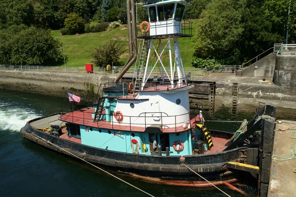 Opdringer sleepboot met verhoogde stuurhuis duwt aak in sloten — Stockfoto