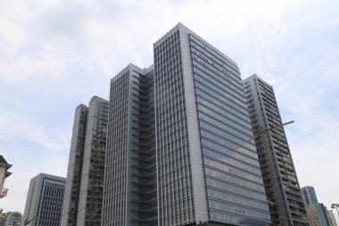 Bir sürü penceresi olan yüksek bir bina. Bina beyaz ve arkasında mavi bir gökyüzü var.