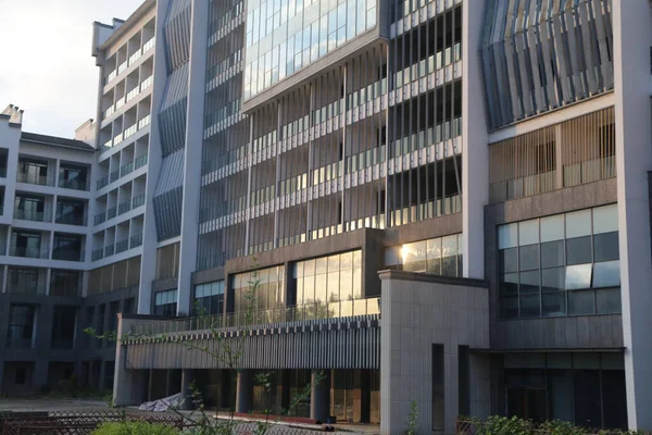 Yeni binanın dış kısmında, gri duvarlar ve beyaz cam perdeli pencereli kentsel bir tarz yer alıyor. Ön cephe güneş ışığını korumak için bir tarafta tahta çıtayı içerirken, somut elementler görüntüsüne görsel derinlik katıyor.