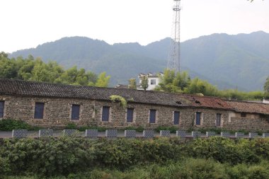 Çin 'in kırsal kesimlerinde, esasen taş duvarlar ve siyah çatı kiremitlerinden oluşan eski bir bina var. Dış duvarın üstünde kırmızı tuğlalar ve altında gri tuğlalar var..