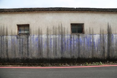 Çin 'de eski bir beton binanın duvarı mavi boyayla boyanmıştır. Duvarların gri tozlu bir dokusu var ve üzerinde hiç pencere yok. Bir tarafta, üç pencere asılı.
