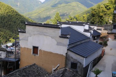 Çin 'in dağlık bölgelerinde, çatılarında siyah fayanslar ve basit duvarlar olan köylerdeki eski evler modern mavi kiremitli güneş panelleriyle değiştirildi..