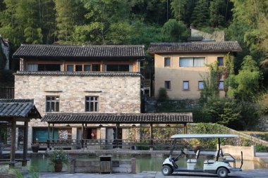 Gable çatısı ve penceresi olan iki taş bina tatil beldesi kasetleri için kullanılan cam ve çelik malzemelerden yapılmış modern evlere dönüştürüldü.