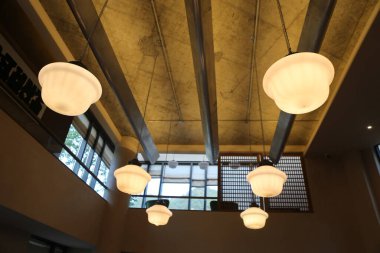 Beton ve ahşap elementlerin yer aldığı, birkaç büyük beyaz cam gölgeli bir endüstriyel binanın tavanının mimari fotoğrafı modern mimariyi gözler önüne seriyor.