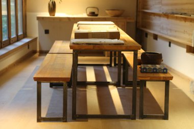 iki uzun masa ve bir bank ile bir yemek masası, her birinin üzerinde mutfak atölyesi olarak kullanılabilecek dört dikdörtgen ahşap tahtalar ya da açık hava toplantılarında servis tabakları vardır..