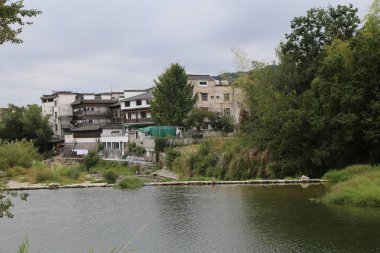 Nehir kıyısının üzerine, önünde su akan ve kenarında yeşil çimenler büyüyen eski bir ev inşa edilir. Hemen yanında çatısı ya da duvarları olmayan bir bina daha var ama sadece bir kat ve beyaz beton bloklar var.