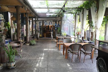 Tayland 'da Tayland sanatı ve mimarisi ile süslenmiş bir açık hava kafe girişinin geniş açılı görüntüsü, bambu veya ahşaptan yapılmış masalar.