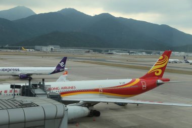 Üzerinde Hong Havayolları yazan kırmızı ve sarı bir uçak. Pistte park halinde.