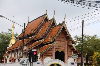 Chiang Mai 'de iki yolun kesiştiği yerde bulunan ve üzerinde trafik ışıkları ve elektrik kabloları olan geleneksel bir Thai tapınağı. Çatı kırmızı kil kiremitlerden yapılmıştır, tepesinde altın kuleler vardır, karmaşık patt ile süslenmiştir.