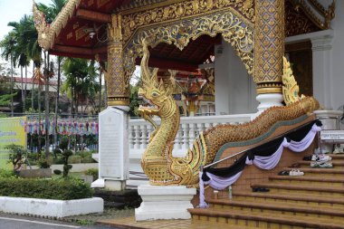 Tapınağın önünde Tayland tarzı ejderha şekilli bir merdiven var. Vücudunda zarif altın ve beyaz desenler var. Her köşesinden sarkıyor renkli kurdeleler.