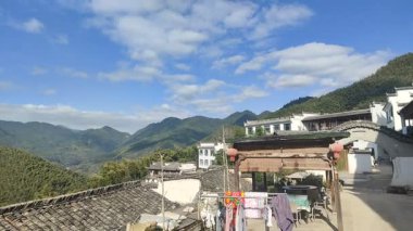 Bir insan, sıcak mutfak ortamında un ahşap bir tahtanın üzerine hamur döker ve pişirmeye hazırlar. Yakınlarda, domates bazlı bir kase peynir ve bitkilerle doldurulmaya hazır.. 