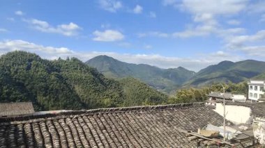 Bir insan, sıcak mutfak ortamında un ahşap bir tahtanın üzerine hamur döker ve pişirmeye hazırlar. Yakınlarda, domates bazlı bir kase peynir ve bitkilerle doldurulmaya hazır.. 