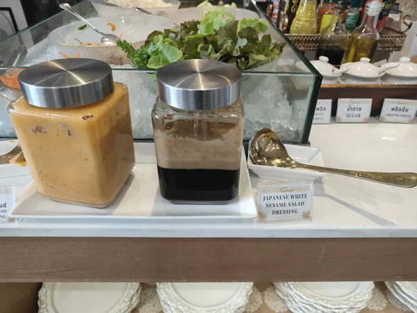 Bir kavanoz sade kahve ve yukarıdakiyle aynı tarzda kehribar renkli bir sos freuesday restoranında yanında salata sosuyla beyaz tabakların üzerine konur.