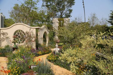 Ev ve bahçe fuarındaki sergi bahçesinde çeşitli çiçeklerle çevrili bir kemer yolu bulunuyor. Peyzaj tasarımı çevresindeki küçük yeşillikleri içerir ve doğal bir atmosfer yaratır..