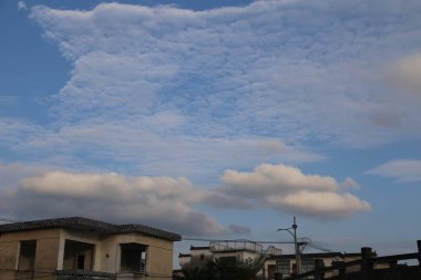 Çin 'deki bir apartmandan alınan gökyüzü mavi gökyüzünde bazı bulutlar gösteriyor. Kamera açısı, resmin bir tarafında daha fazla bulanık alan ve detay yakalamak için hafifçe eğik..