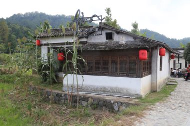 Güney Çin 'in kırsal kesimlerinde çatısı boyunca asılı kırmızı fenerlerle süslenmiş beyaz duvarları ve siyah fayansları olan eski bir ev var. Önünde mısır yetişiyordu. Olay yerini en son yakından incelediğimde.