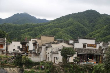 Çin 'in Anhui eyaletinin dağlarında küçük bir köy. Binaların bir tarafında beyaz duvarlar ve siyah fayanslar var. Etrafı yeşil bitki örtüsüyle çevrili..