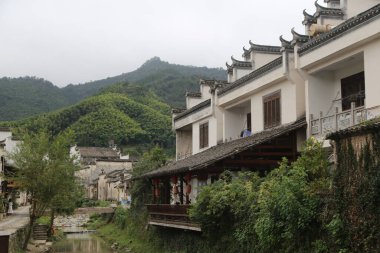 Köyde, üzerinde yeşil dağlarla çevrili beyaz duvarlar ve siyah fayanslar olan bir grup Çin tarzı bina. Nehir içinden akar ve kadim bir atmosfer yaratır..