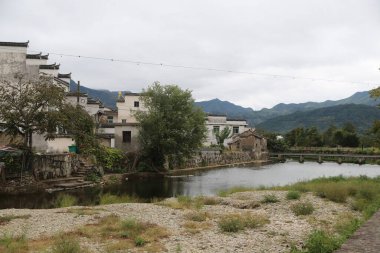 Her iki tarafında beyaz duvarlar ve gri fayanslar olan küçük bir nehir köyün içinden akar. İnsanların geçebileceği eski bir taş köprü var. Önümde yeşil bir sıradağ vardı.