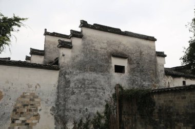 Çin 'in kırsal kesimindeki eski binada beyaz duvarlar ve gri fayanslar var. Yıpranmış duvar yosunla kaplı, tarihi cazibesini sergiliyor. Bir tarafında pencere yok..