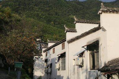 Klasik Hui tarzı mimarinin pitoresk bir sokak manzarası. Beyaz duvarlar ve belirgin koyu renkli, at başlı gablonlar. Modern klimalar dış yüzeylere monte edilir, eski ve yeni karışımı gösterilir. Bir hurma ağacı fusu.