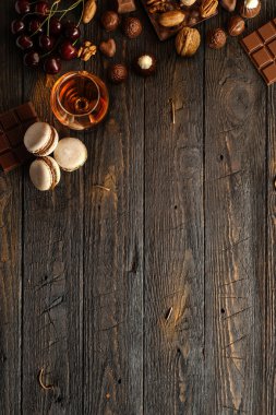 Macaarons, fındık, çikolata ve kiraz ahşap bir masa üzerinde. Metin için yer