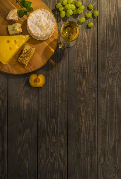 Peynir, üzüm ve beyaz şarap ahşap masa. Metin için yer