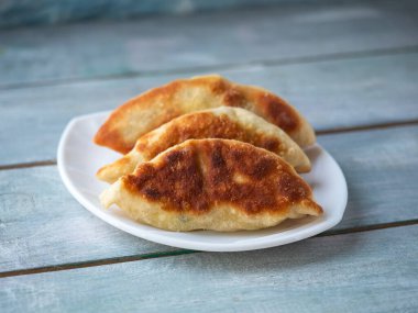 Tahta bir turkuaz tepsinin üstünde duran beyaz bir tabakta ev yapımı turtalar.