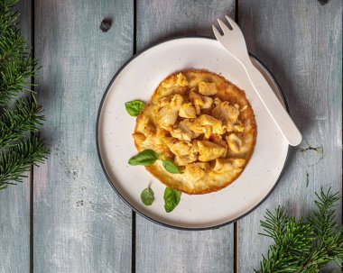 Tahta tepside, yuvarlak tabakta yumurta omletinde kızarmış tavuk eti.