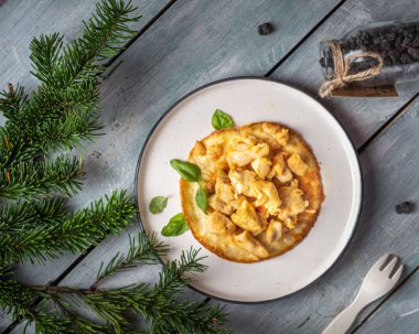 Protein kahvaltısı. Yuvarlak tabakta yumurta omletinde kızarmış tavuk eti. Yukarıdan bak. Köknar dallarıyla süslenmiş mavi bir tepside servis edilir.