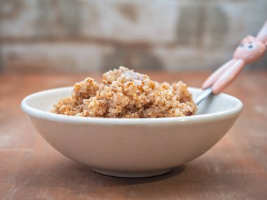 Kırmızımsı arka planda, beyaz bir tabakta, buğday lapası.