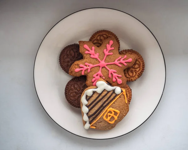 Multi-colored gingerbread cookies with colorful icing on a white plate top view