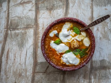 Köy çorbası, sebzeli ve köfteli, derin bir tabakta, kaşıkla yakın plan.