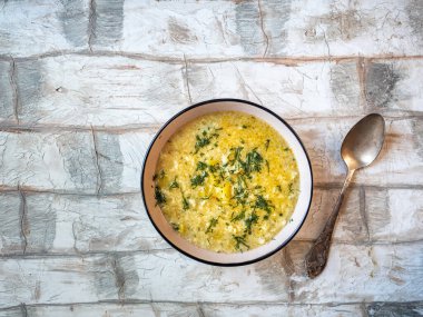 Seramik tabakta yeşil dereotlu patates ve hamur tatlısı ve kaşık üstü manzaralı çorba.