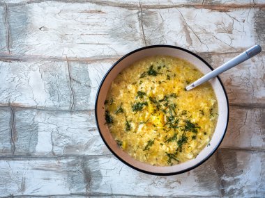 Köfteli sıcak çorba ve derin yuvarlak bir tabakta dereotu ve açık masa manzaralı bir kaşık.