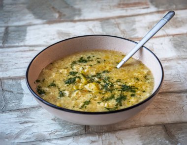 Çorba, hamur köftesi ve derin bir tabakta otlar ve yakın plan bir kaşıkla.