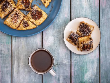 Ev yapımı kurabiyeler ve siyah kahveyle birlikte, beyaz bardakta, ahşap mavi tepside kahvaltı.