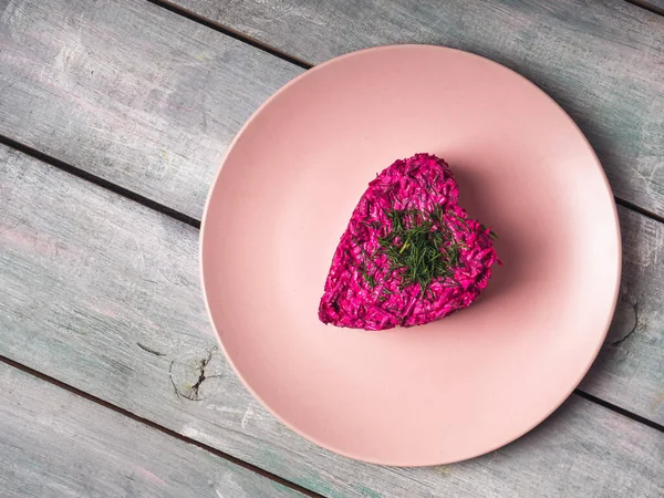 Bietenwortelsalade in de vorm van een hartje op een roze bord — Stockfoto