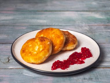Hafif seramik tabakta ahududu reçelli peynirli kekler. Tahta tepside lezzetli bir kahvaltı.