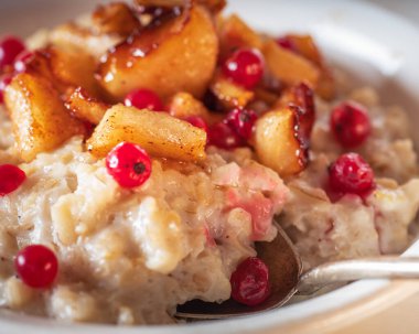 Meyve ve meyveli yulaf ezmesi, elmalar, böğürtlen ve tarçın kaşıkla yakın plan.