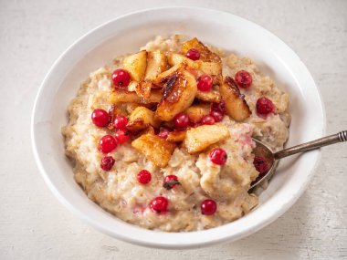 Sütlü ve meyveli yulaf ezmesi, beyaz bir tabakta ve antika bir kaşıkla yakından.