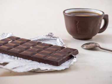 Kahverengi seramik bardakta doldurulmuş koyu çikolata ve kahve, beyaz masada çay kaşığı