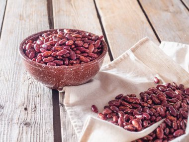 Seramik tabakta kırmızı fasulye ve ahşap bir masada keten peçete.